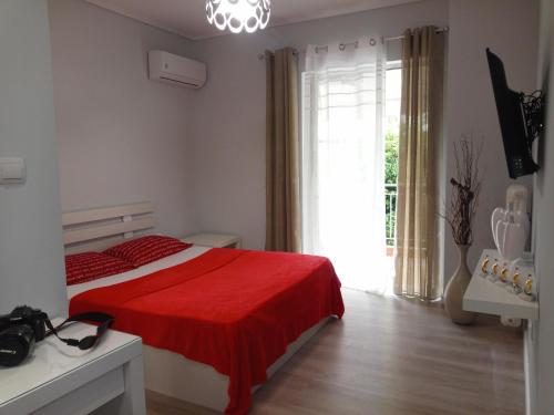 a bedroom with a bed with a red blanket and a window at Studio NATASHA in the area of Kallithea in Athens