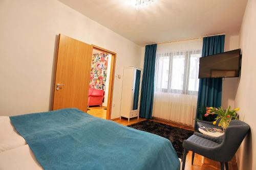 a bedroom with a bed and a television and a chair at Paradise Apartman in Miskolc