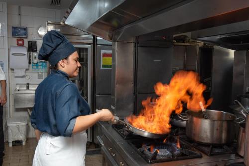 a person cooking food in a pot on a stove at Novotel RJ Santos Dumont in Rio de Janeiro