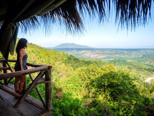 a woman standing on a fence looking out over a valley at Ecolodge Tubagua Puerto Plata in Tubagua
