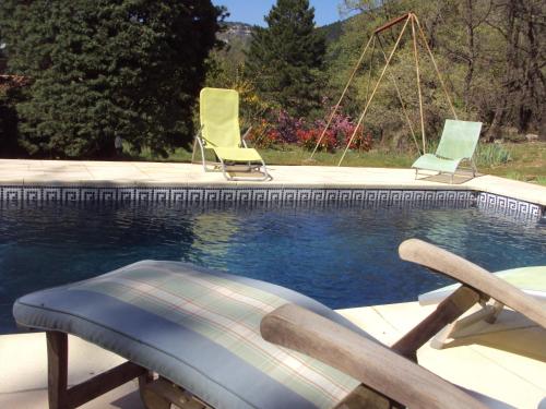 une piscine avec trois chaises et une balançoire dans l'établissement Les Rochers, à Saint-Étienne-de-Gourgas