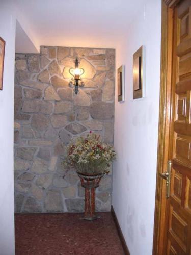 a vase of flowers in a hallway with a stone wall at Casa Herrero in Oto