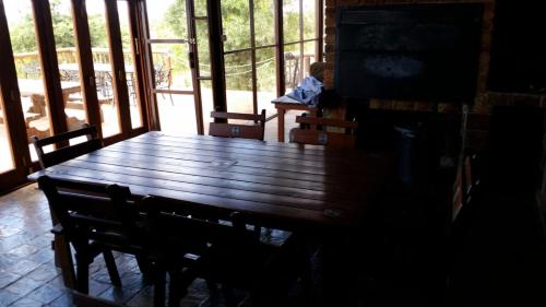 a large wooden table in a room with windows at Hadeda Lodge, Mabalingwe in Warmbaths