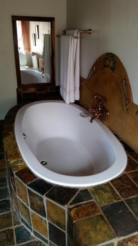 a large bath tub in a bathroom with a mirror at Hadeda Lodge, Mabalingwe in Warmbaths