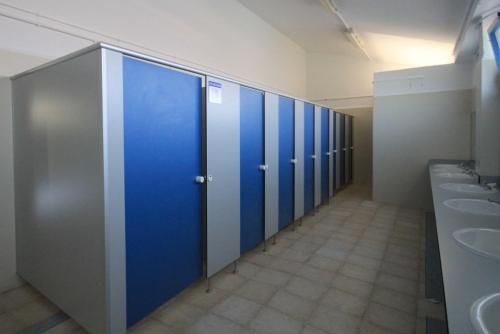 a row of blue stalls in a public restroom at Camping Mola! Surf Loredo in Loredo
