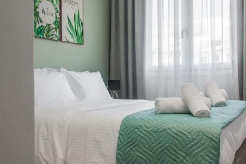um quarto com uma cama com lençóis brancos e almofadas em Central Green Studio em Heraclião