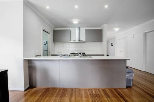 a white kitchen with a sink and a counter at Holiday Rose in Point Cook