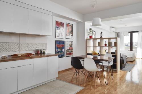 a kitchen with white cabinets and a table and chairs at Moodeight Apartments in Skopje