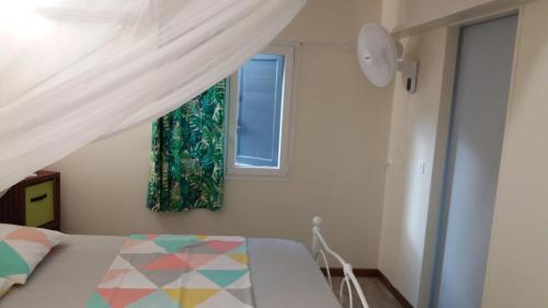 Schlafzimmer mit einem Bett und einem Fenster in der Unterkunft Gîte Bananier in Bouillante