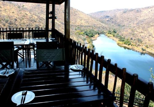a porch with a table and chairs and a view of a river at Hadeda Lodge, Mabalingwe in Warmbaths