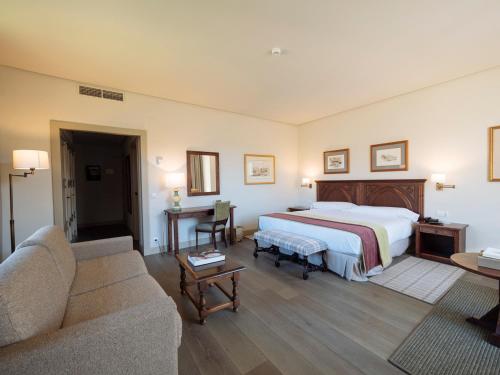 a hotel room with a bed and a couch at Parador de Cangas de Onís in Villanueva de Cangas de Onís