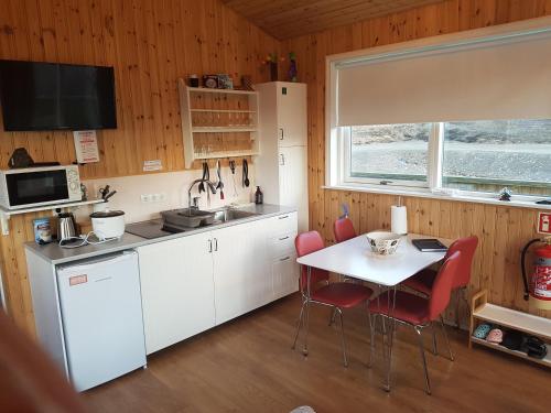 a kitchen with white cabinets and a table with red chairs at Silva Holiday Home in Eyjafjaroarsveit