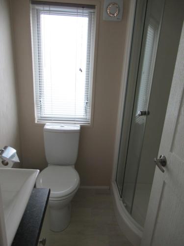 a bathroom with a toilet and a shower and a window at Lodge 283 in Saint Enoder