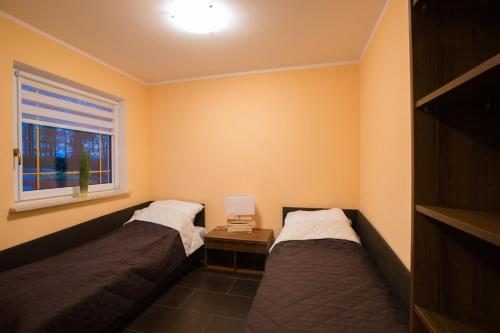 two beds in a room with a window at Domki letniskowe Deluxe in Dąbki