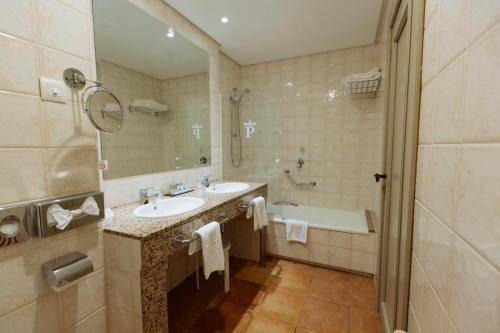 a bathroom with two sinks and a tub and a shower at Parador de Cangas de Onís in Villanueva de Cangas de Onís