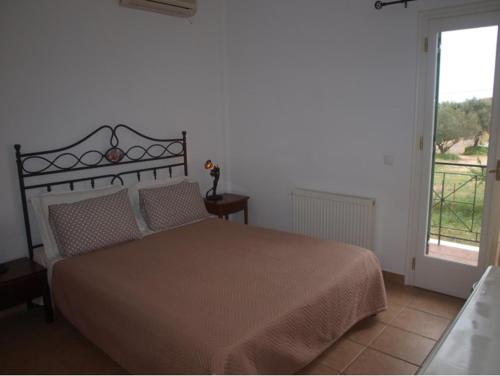 Un dormitorio con una cama grande y una ventana en Villa Moschona, en Lakíthra