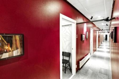 a hallway with red walls and a chair in a room at Ramilton Old Town Hostel in Stockholm