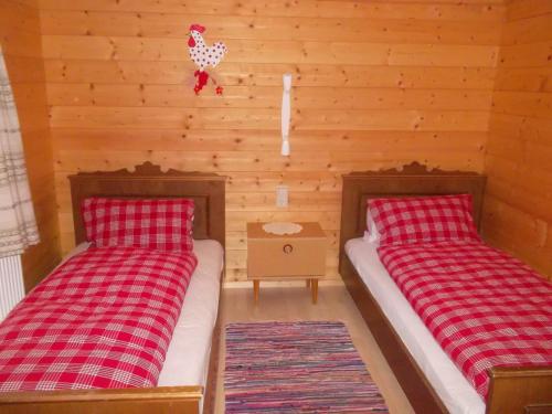two beds in a room with wooden walls at Riepleralm in Matrei in Osttirol