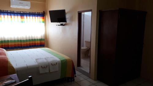 a bedroom with a bed and a window and a television at Hotel Alebrijes in San Pedro Pochutla