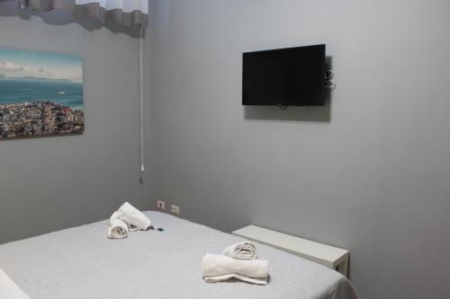 una camera da letto con letto, asciugamani e TV a schermo piatto di Central Station Garibaldi a Napoli