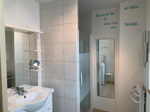 W białej łazience znajduje się umywalka i lustro. w obiekcie Appartement cosy proche plage et centre ville w mieście Granville