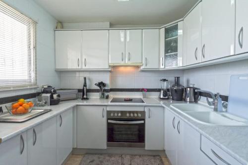 a white kitchen with white cabinets and a sink at Apartment next to the beach in Portals Nous