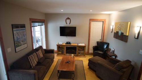a living room with two couches and a tv at Cedar House Restaurant & Chalets in Golden