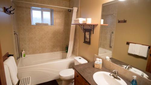 a bathroom with a tub and a toilet and a sink at Cedar House Restaurant & Chalets in Golden