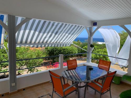 een balkon met een glazen tafel en stoelen en de oceaan bij LOCBIR in Le Diamant