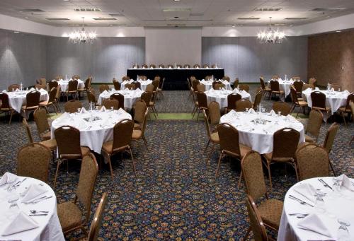 a dining room with tables and chairs with white tablecloths at Ramkota Hotel - Casper in Casper