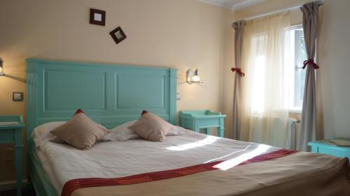 a bedroom with a bed with a blue headboard and a window at Hotel Bastion in Sinaia