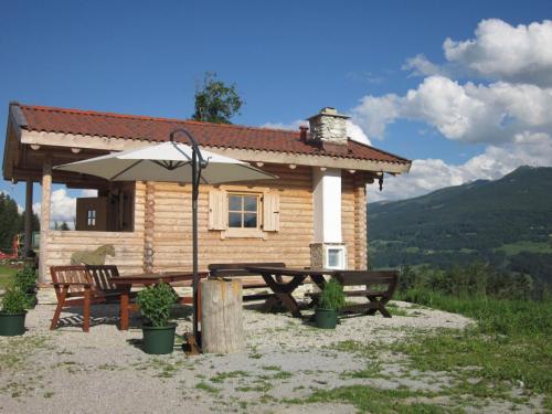 a log cabin with a picnic table and an umbrella at Appartement zum Rössl in Ramsau am Dachstein