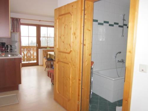 a bathroom with a wooden door and a bath tub at Appartement zum Rössl in Ramsau am Dachstein