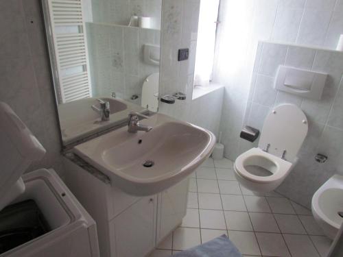 a white bathroom with a sink and a toilet at Appartamenti Rumo in Rumo