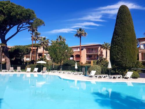 une grande piscine avec des chaises longues et des palmiers dans l'établissement Ecrins de la Badine- pinède, à Hyères