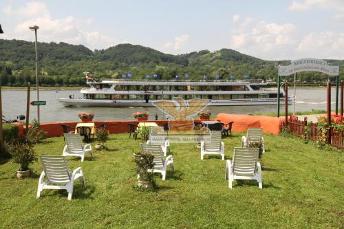 a group of chairs sitting on the grass with a boat at Rheinhotel Bellavista in Braubach