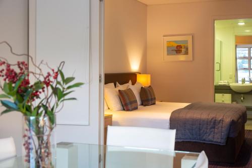 a hotel room with a bed and a vase of flowers at Marina Apartments - Element Escapes in Queenstown