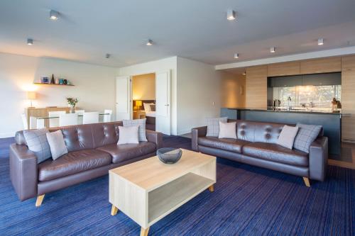 a living room with two leather couches and a table at Marina Apartments - Element Escapes in Queenstown