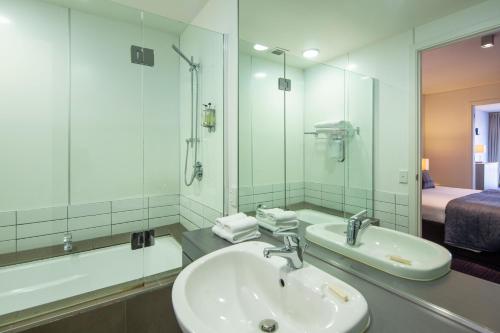 a bathroom with a sink and a mirror and a bed at Marina Apartments - Element Escapes in Queenstown