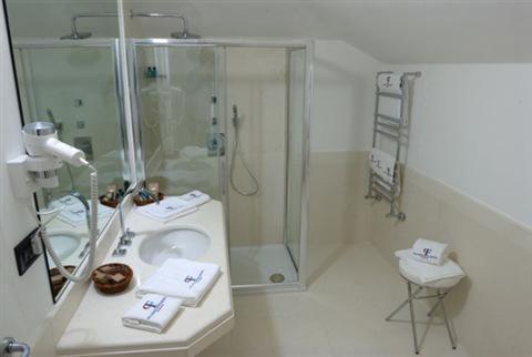 a white bathroom with a shower and a sink at Palazzo Foti Hotel in Crotone