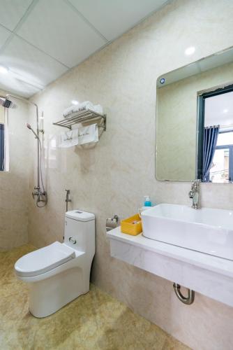 a bathroom with a sink and a toilet and a mirror at Peaceful House Hostel in Dong Hoi