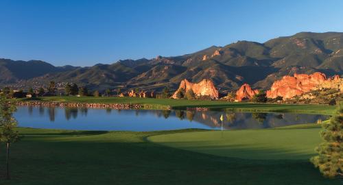 a golf course with a lake and mountains in the background at Garden of the Gods Resort & Club in Colorado Springs