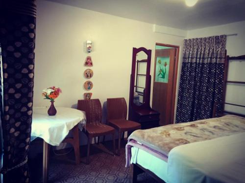 a room with two beds and a table and chairs at Moon Plain Inn in Nuwara Eliya