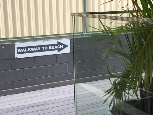 a sign for a walkway to beach on the side of a building at Burleigh Palms Holiday Apartments in Gold Coast
