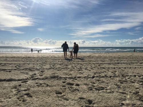 three people and a dog standing on the beach at Burleigh Palms Holiday Apartments in Gold Coast
