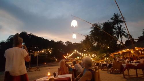 a group of people sitting at tables watching the sunset at Home No.9 in Ko Lanta