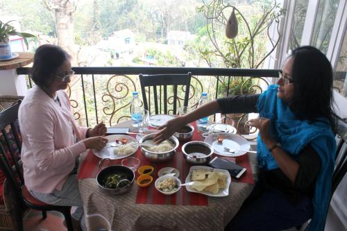 two women sitting at a table eating food at Mansarover Home Stay in Kalimpong