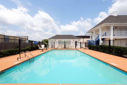 a swimming pool with a fence and a house at Baymont by Wyndham Prattville - Montgomery in Prattville