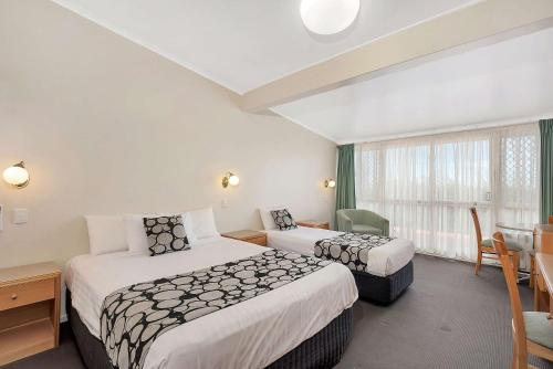 
a hotel room with a bed, chair, and nightstand at Econo Lodge Toowoomba Motel & Events Centre in Toowoomba
