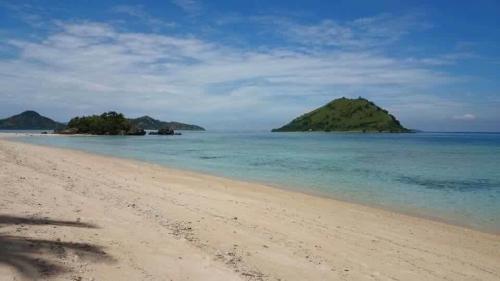 a beach with a small island in the water at Boneputeh Homestay in Taliwang